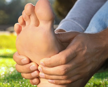 Man sitting barefoot on fresh green grass outdoors, closeup