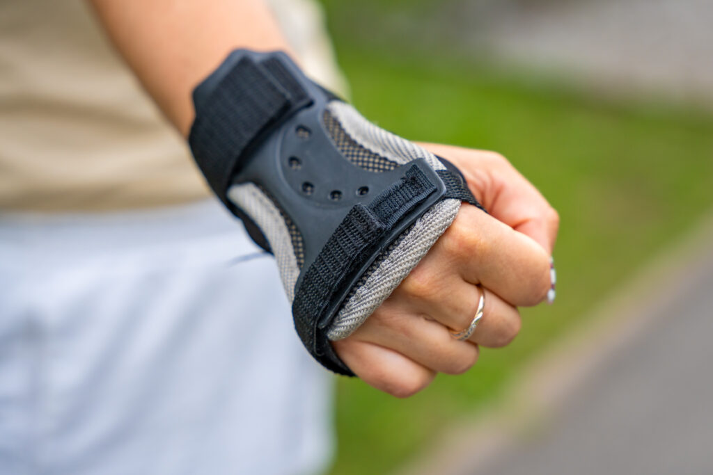 Close up view of hand in protection glove of roller skater woman in inline skates rollerblading in park. Outdoor activities. Summer roller skating.